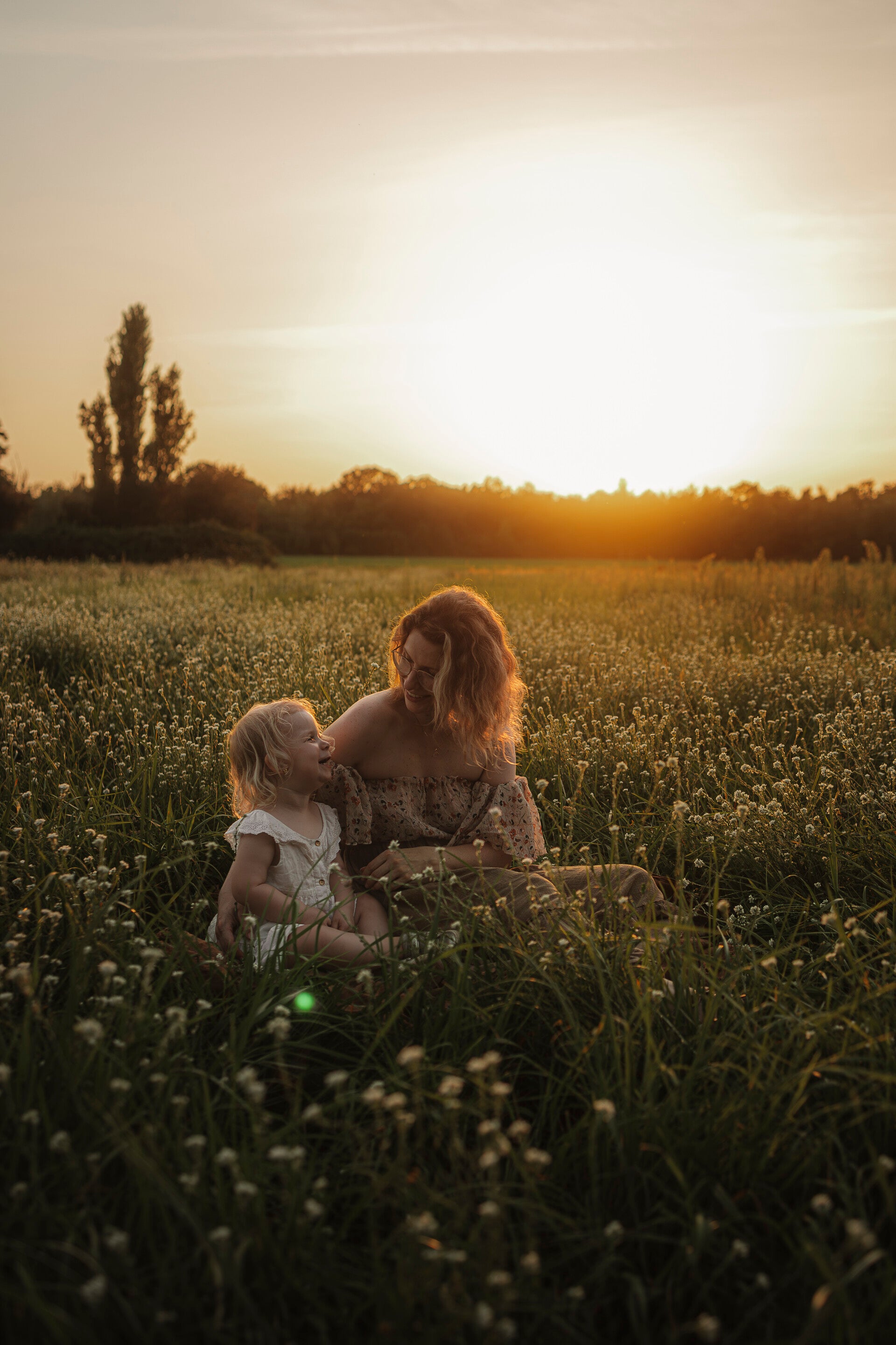 Pärchen steht in vertrauter Pose am wasser und blickt auf den Babybauch beim Babybauchshooting in Berlin 