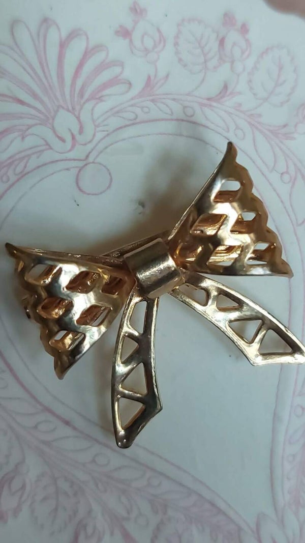 Een latté‑gouden strikbroche met Parisienne Allure