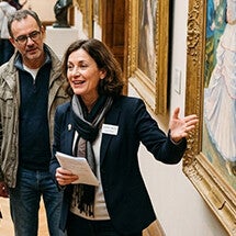 Une guide de musée commente avec animation un tableau devant un groupe