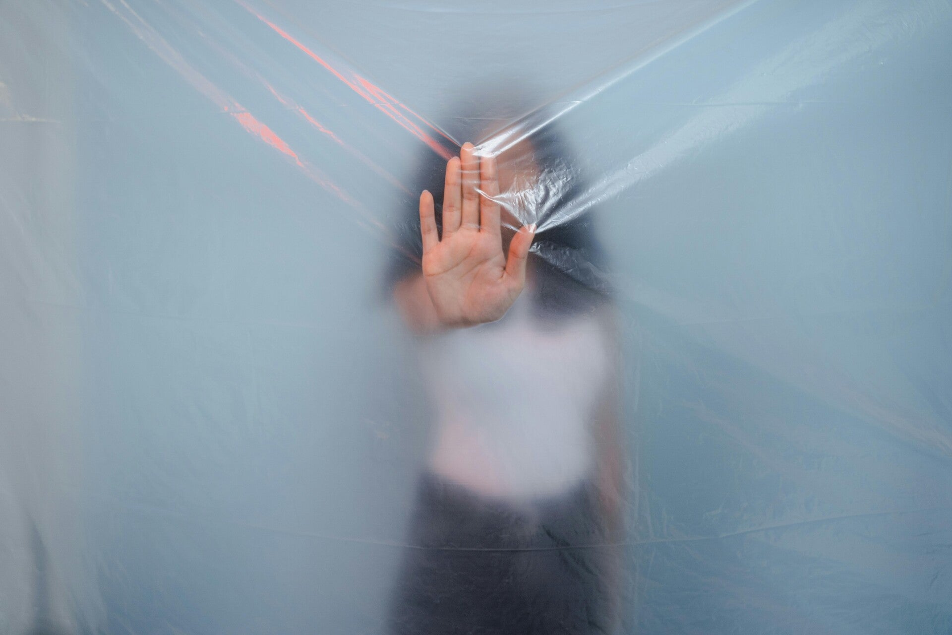 Woman pushing her hand against the bubble she is in. Likewise, Social Media algorithms create an invisible bubble that surrounds us.