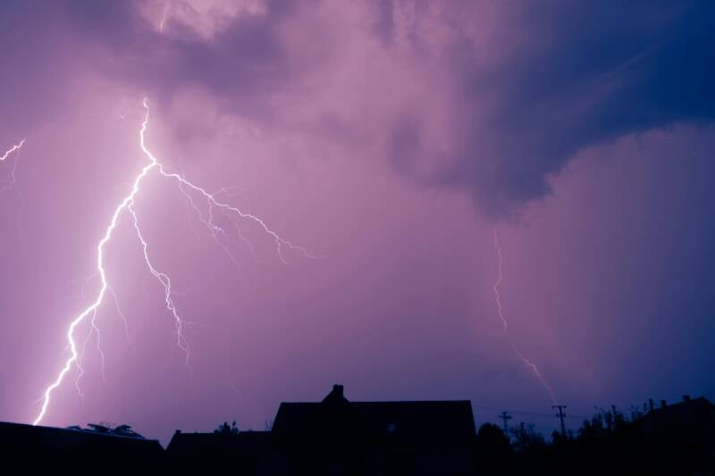 A jagged lightning bolt striking the ground, displaying a branching fractal pattern against a dark purple storm sky.