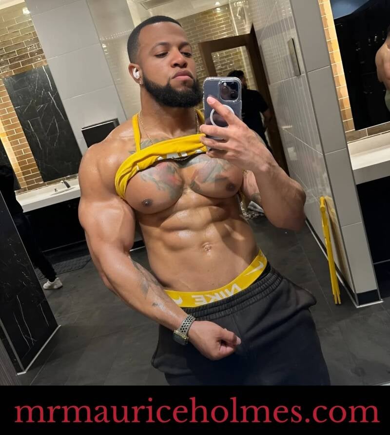 Buff masculine fitness coach Maurice Holmes showing off six pack, huge chest, and tattoos–representing physical fitness, body goals, and discipline.