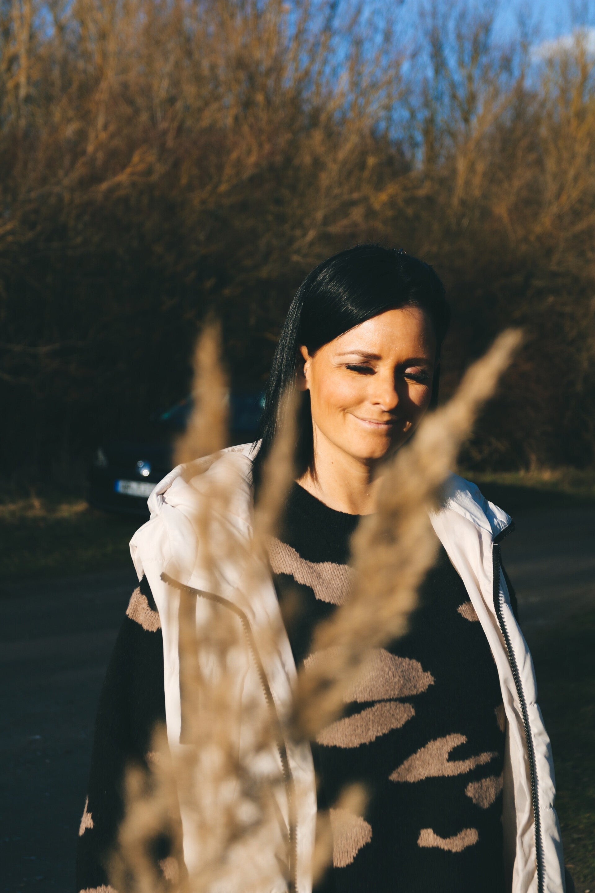 Portrait einer Frau zwischen Gräsern im warmen Abendlicht