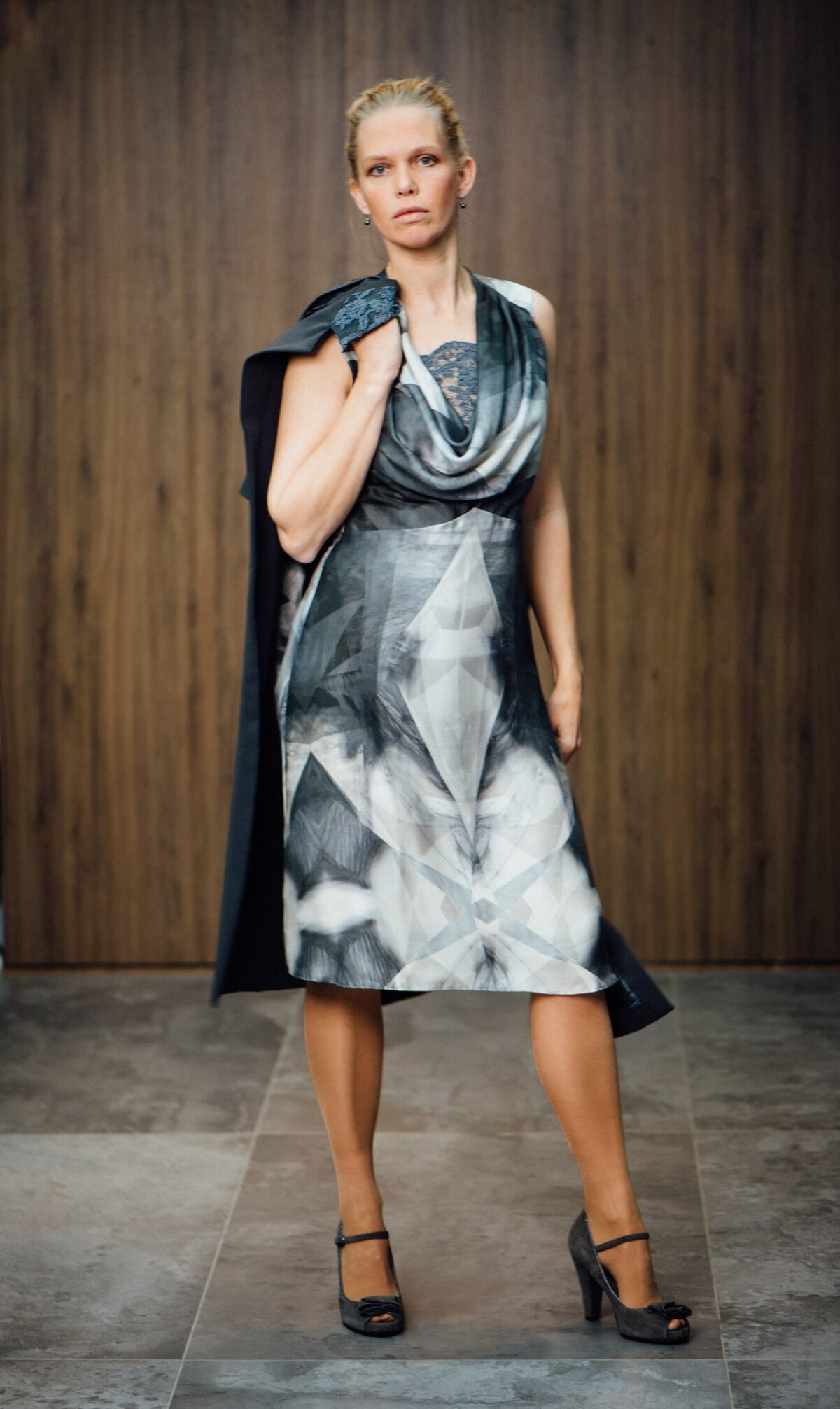 Jurk en cape combinatie, donkergrijze abstracte print, een watervalhals en kanten details. Maatwerk van Modestudio Jacoba.