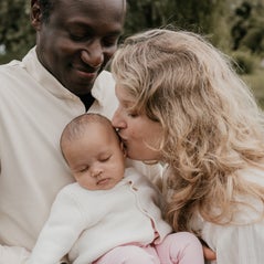 Een mama die haar newborn een kusje op het hoofdje geeft