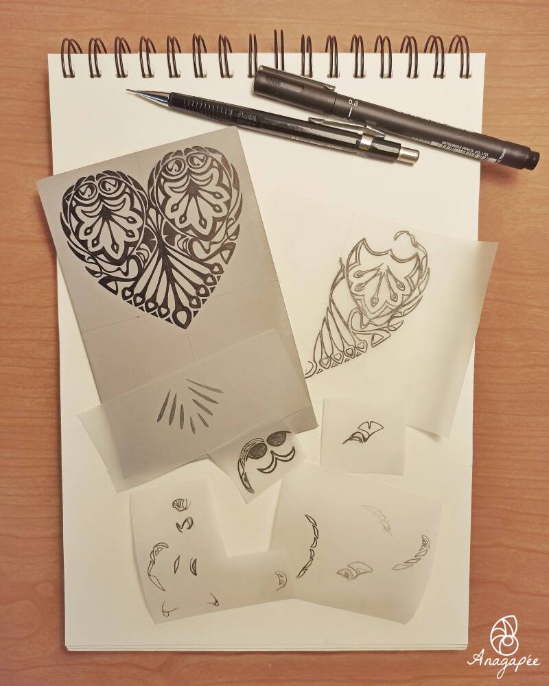 Bloc de papier dessin à spirales sur lequel on retrouve différents bouts de papier calque, une plaque de linoleum, un critérium et un marqueur. Il s'agit des différents parties du dessin pour la linogravure du coeur, et son report sur le lino, prêt à être