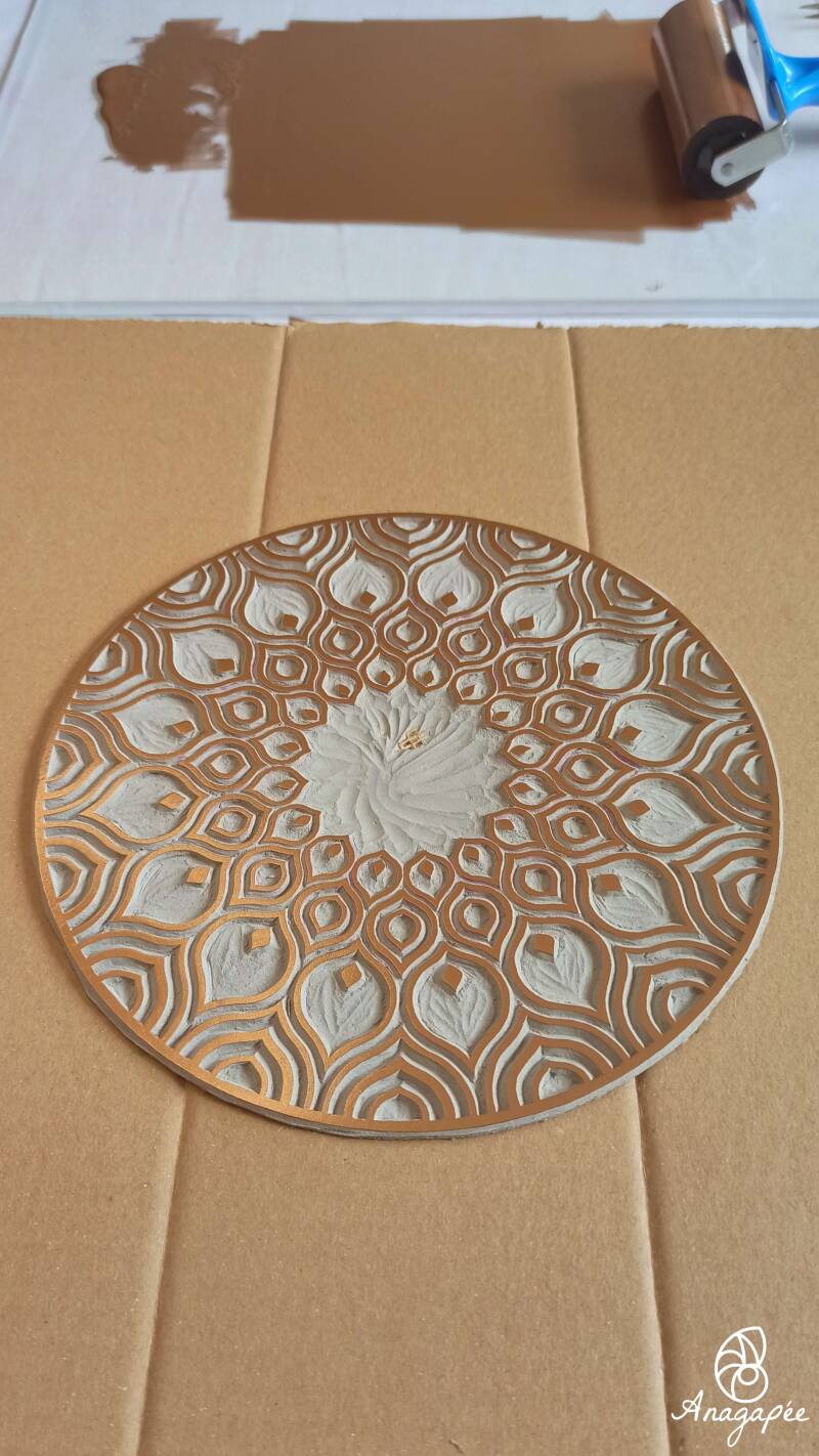 En haut, rouleau et encre cuivrée travaillée sur la plaque de verre. En bas, linogravure du mandala encrée sur du carton. Elle est prête pour l'impression manuelle.