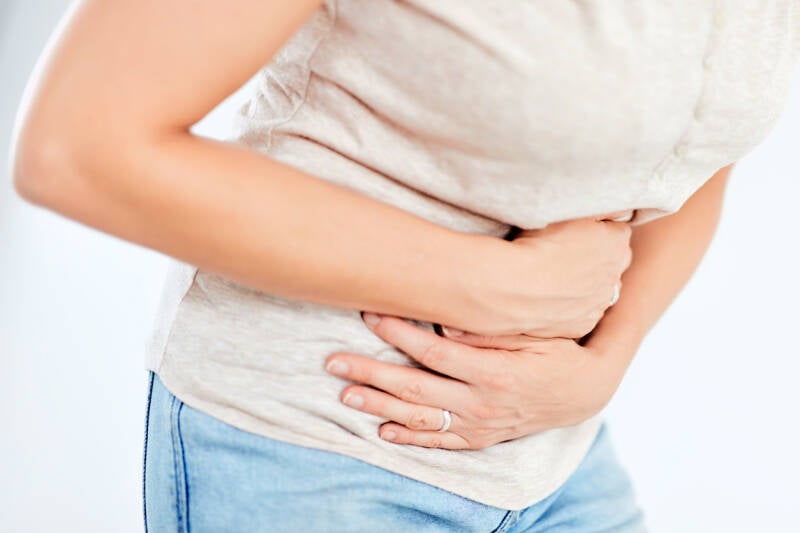 Das Bild zeigt eine Frau, die sich schmerzend den Bauch hält. Rote Markierungen deuten auf Schmerzen hin, die auf Erkrankungen innerer Organe hindeuten.