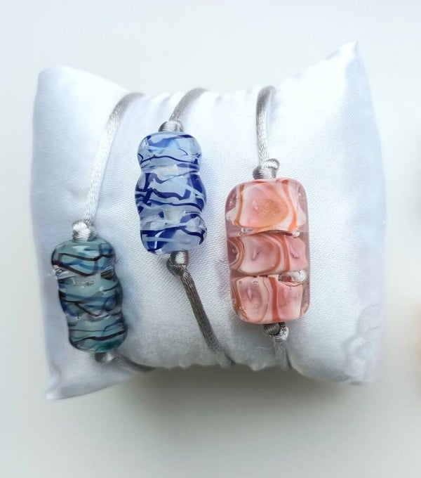 Armbandje van satijnkoord met grote drie in 1 bedel er aan. Blauwtint