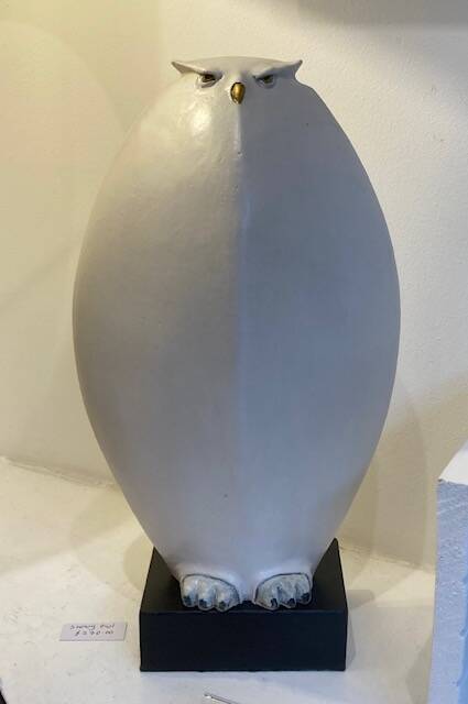 Upright snowy owl sculpture mounted on black plinth