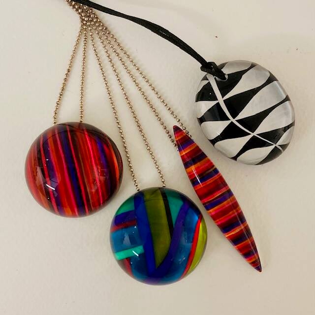 3 brightly coloured chunky resin pendants on silver chains and one black & white oval pendant on a leather thong by Brighton jeweller Rowena Parks