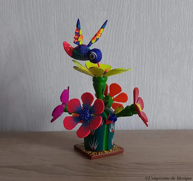 Sculpté par les artisans zapotèques de l'atelier Alebries de Madera, cet alebrije représente la danse des colibris pour la récolte des âmes sur les fleurs de cactus