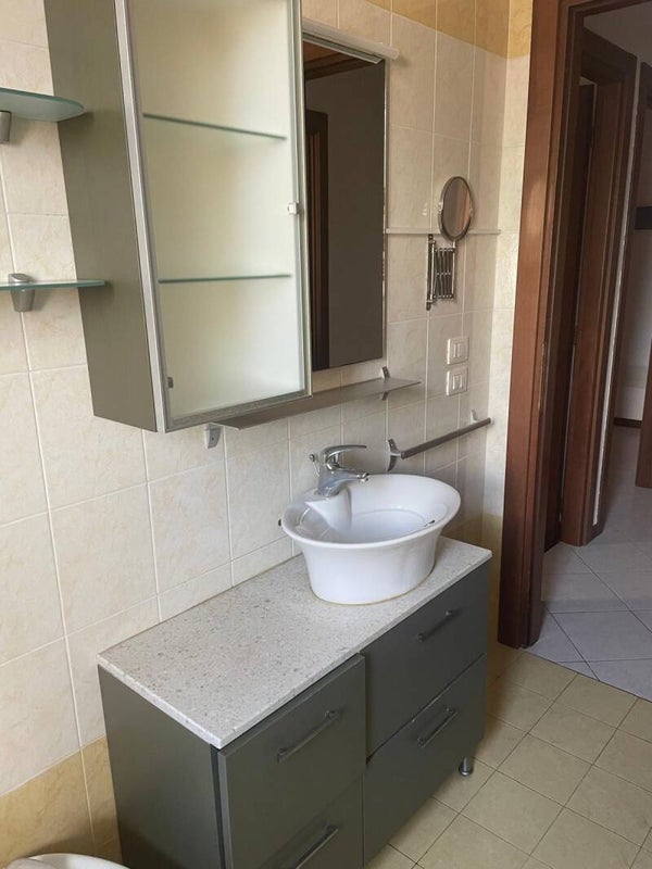 Mobile da bagno con finiture grigie, ampia base completo di lavabo, pensile coordinata e specchiera.