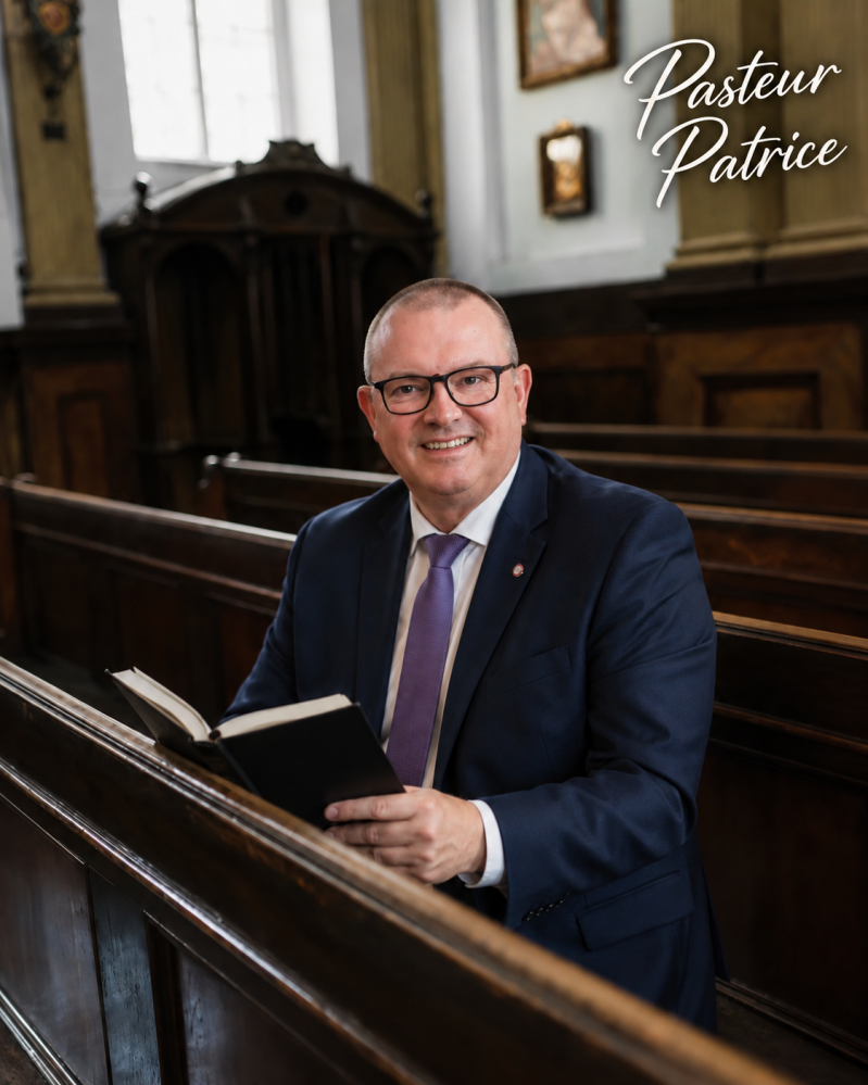 « Pasteur Patrice, souriant dans une église, une Bible ouverte entre les mains. »