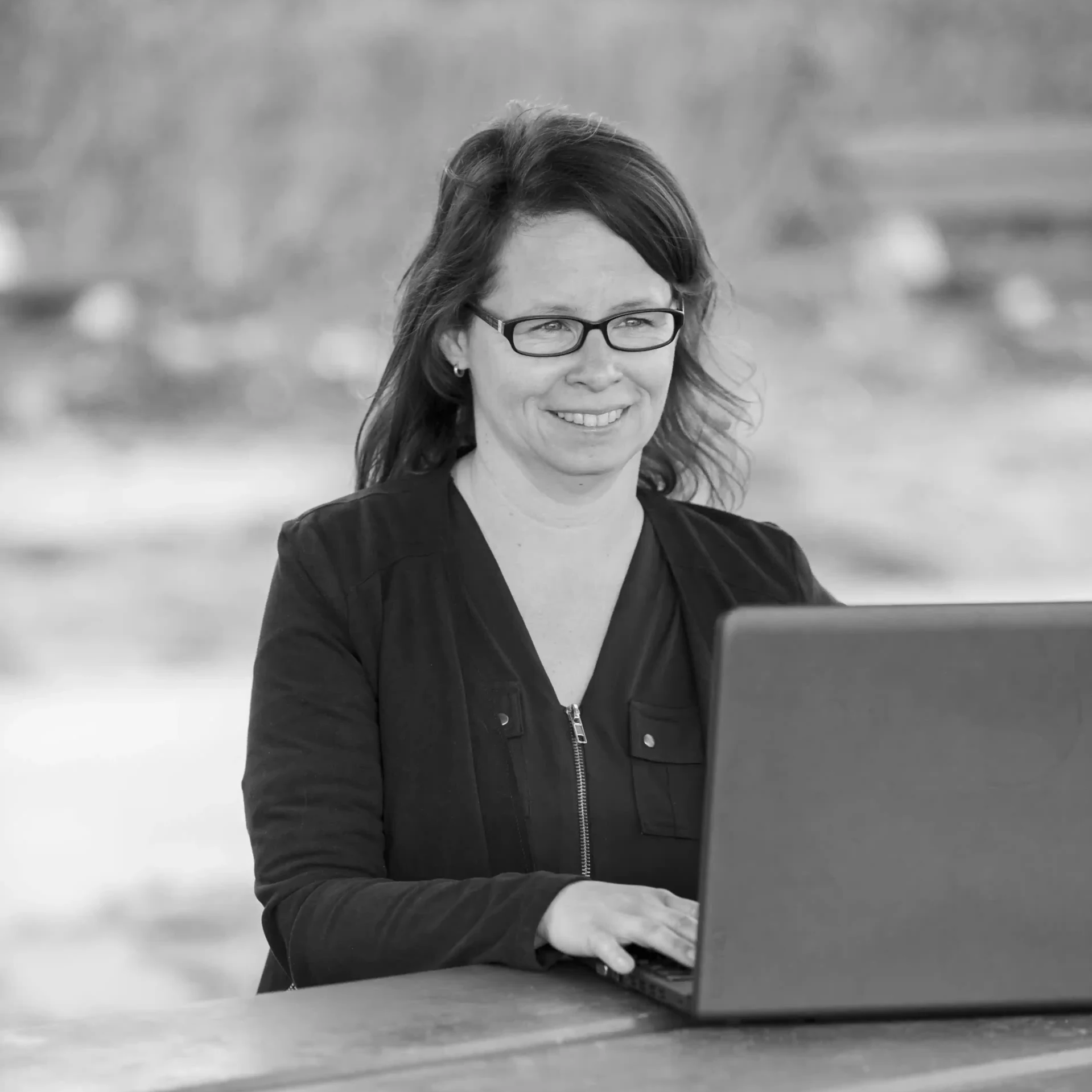 Annica Keichel - virtuelle Office Management sitzt auf einer Parkbank am Laptop