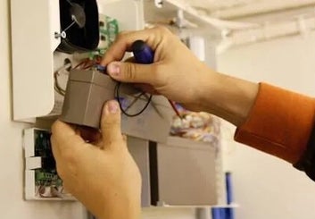 Un technicien en systèmes de sécurité réalise la maintenance d'une centrale d'alarme intrusion.
