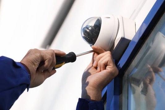 Un technicien alarme installant une caméra de vidéosurveillance sur un mur.