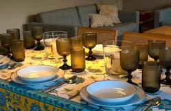 Mesa decorada con mantel floral, vajilla blanca y copas de vidrio ámbar, lista para una comida en grupo en Armaño 12.