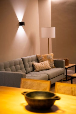 Rincón de salón acogedor con sofá gris, cojines estampados y lámpara de pie junto a una mesa auxiliar en Armaño 12.