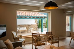 Salón de Armaño 12 con sillones tapizados y ventanales que ofrecen vistas al porche cubierto con mobiliario de exterior.