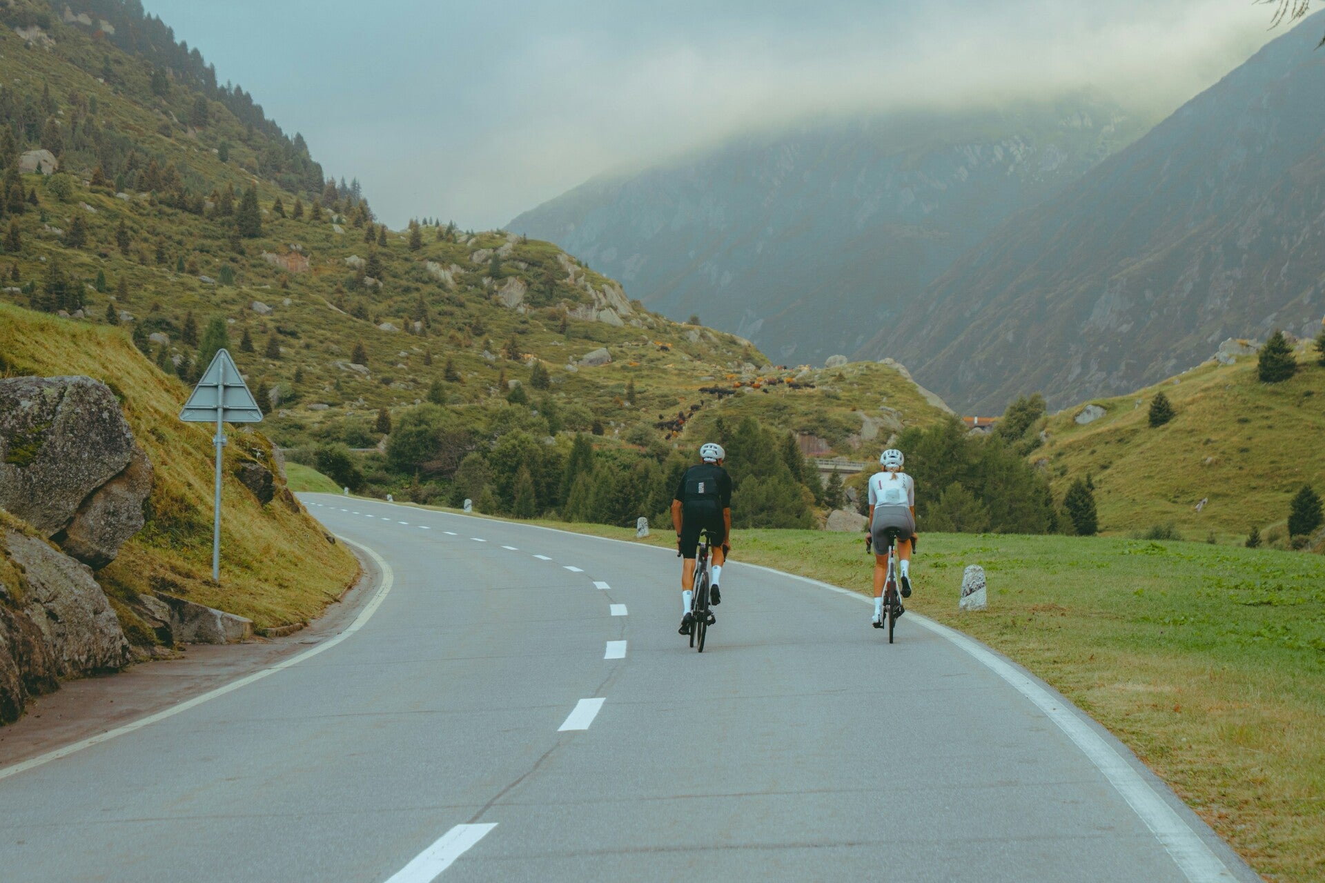 Two road cyclists riding through Swiss mountain scenery