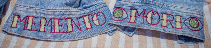 Close-up of the jacket sleeve showing colorful machine embroidered tattoo-inspired designs stitched edge to edge.