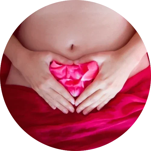 Manos formando un corazón sobre el vientre, reconexión con el útero