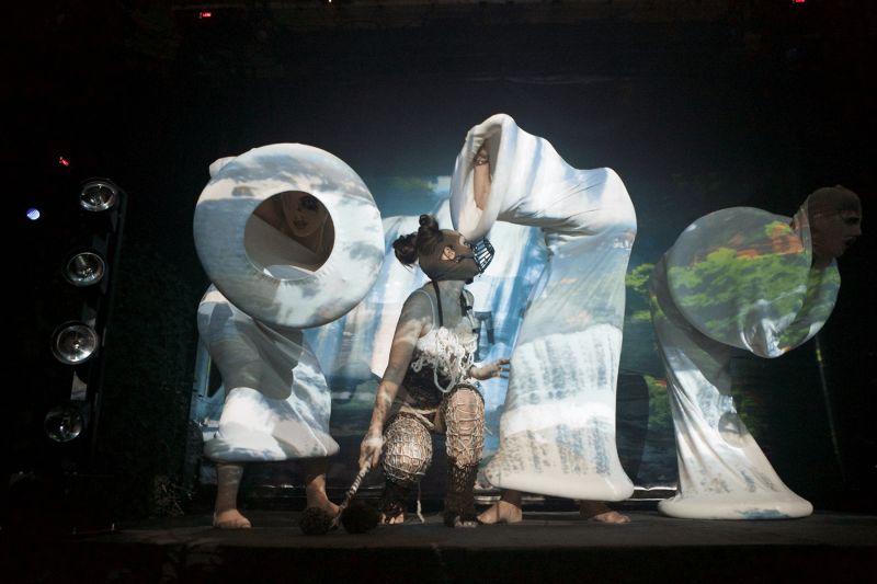  Woman wearing muzzle and knitted catsuit looking at cocoons performance