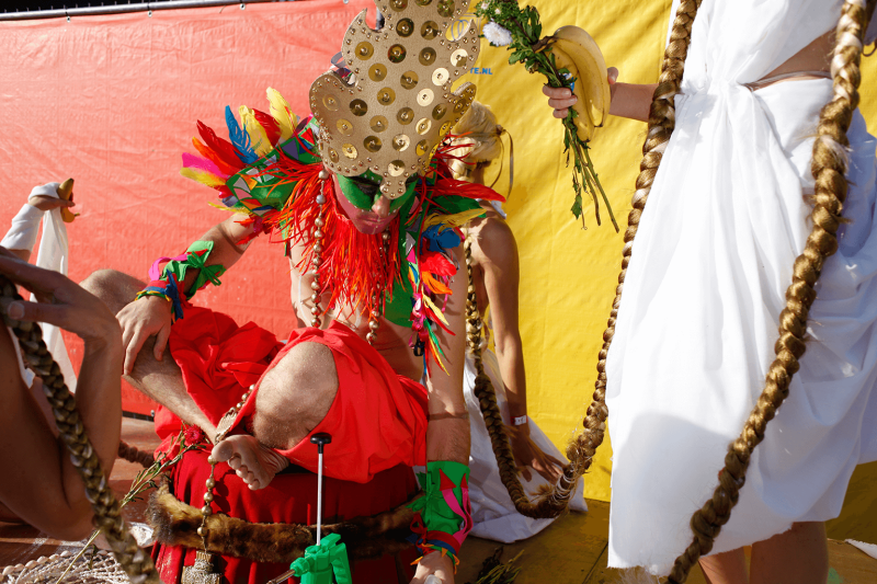 Man wearing a feather collar and golden headpiece at a festival
