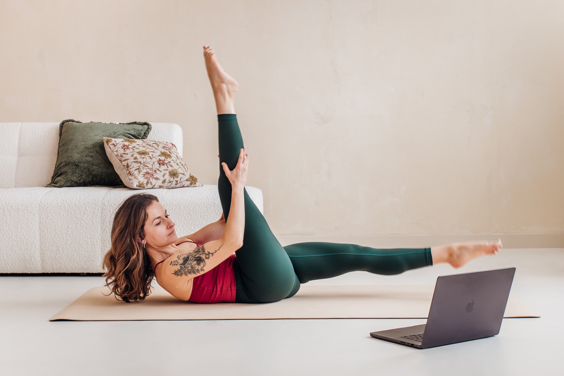 Pilates mat exercise performed at home with a laptop used for an online class