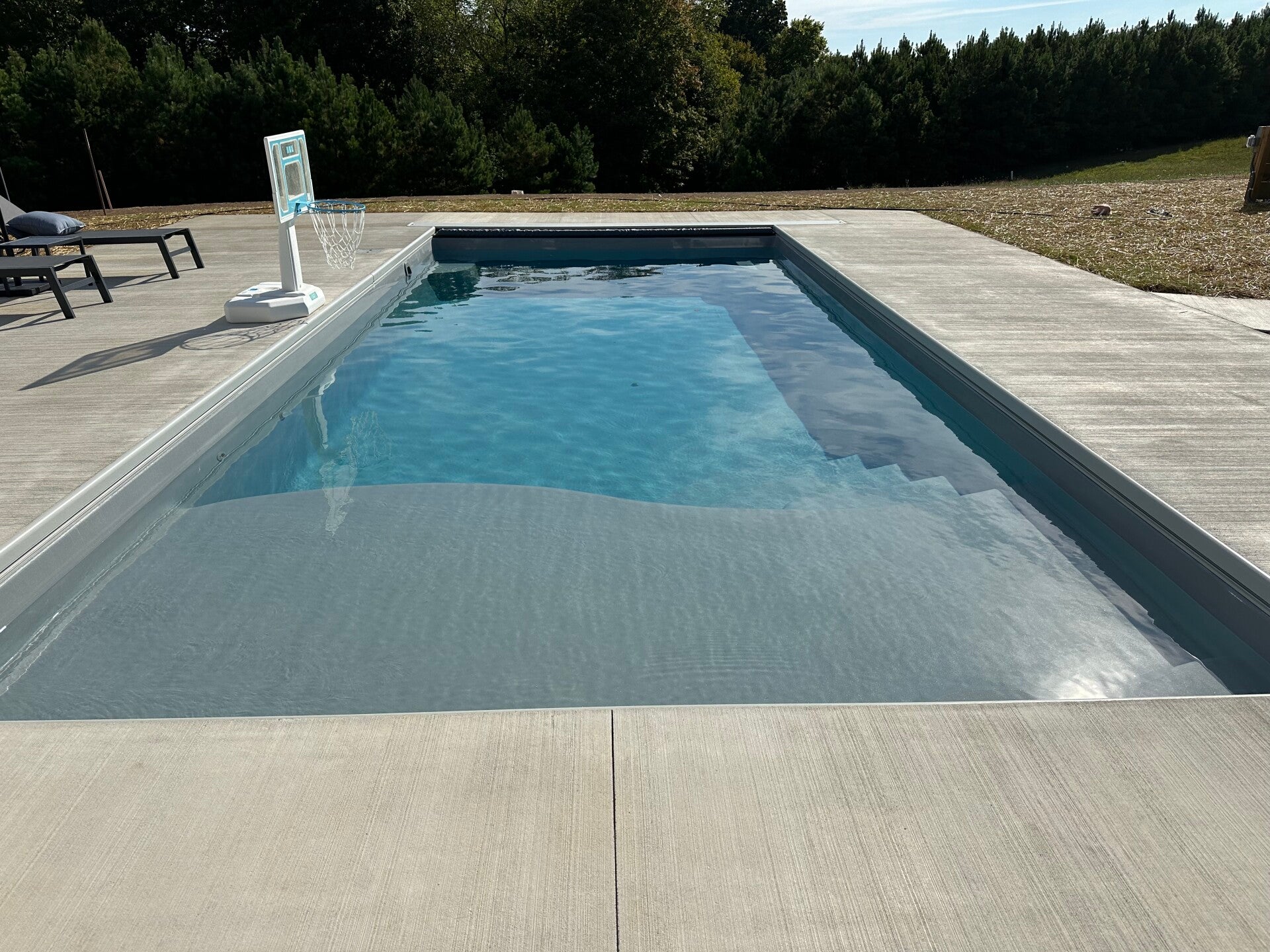 A rectangular pool with a wide concrete surround.