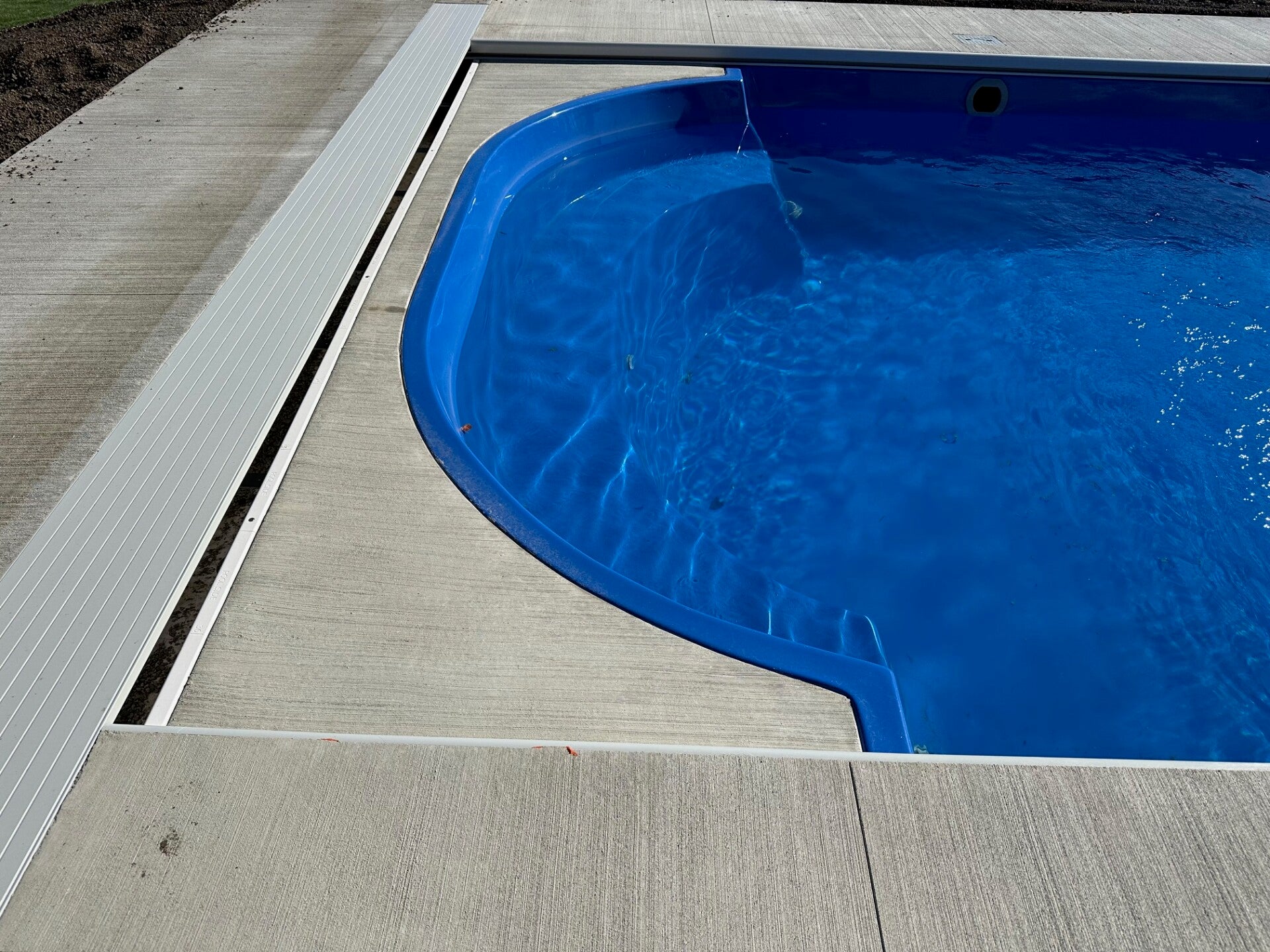 A closer view of the pool edge, curved entry, and cover track.