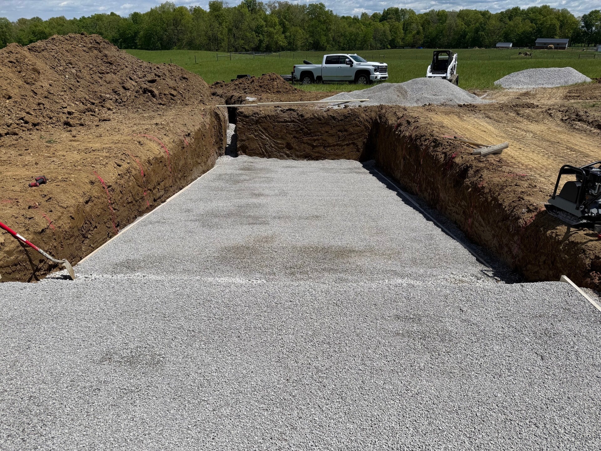The excavated site and gravel base prepare the space for the fiberglass shell.