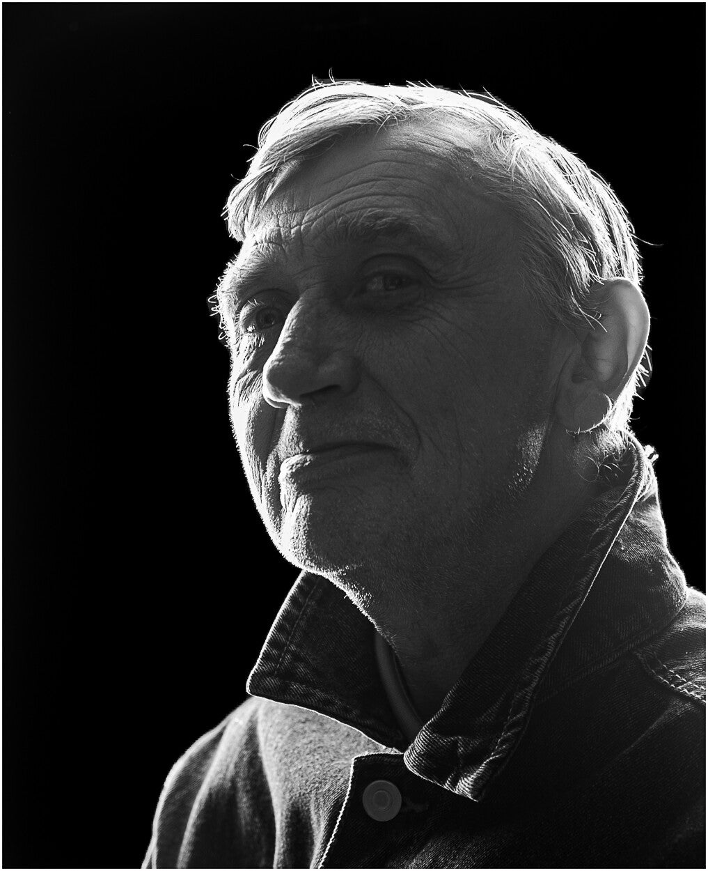Black and white portrait of Paul photographed from a low viewpoint, looking upward with rim lighting against a black background.