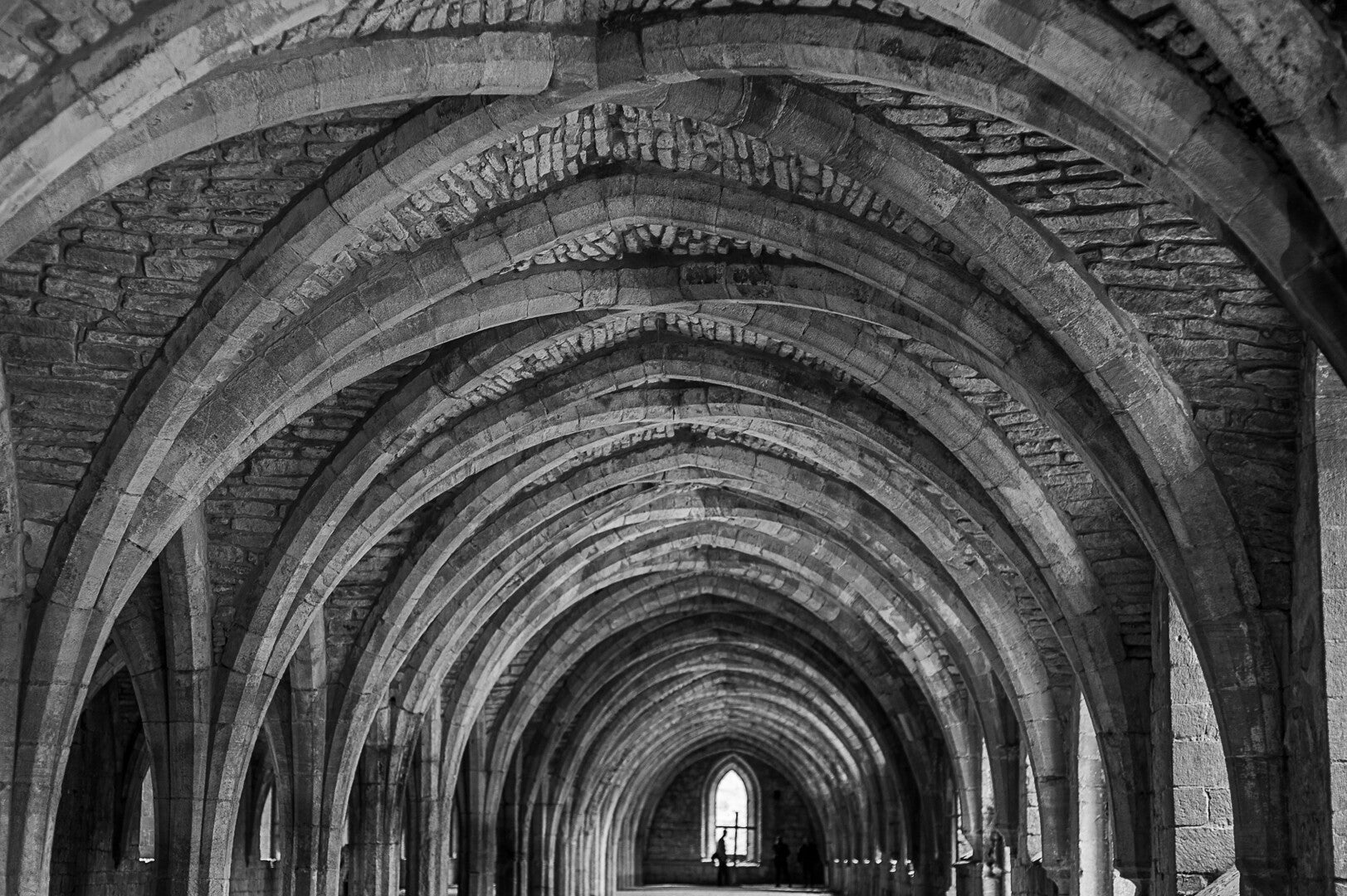 Black and white photograph of repeating stone arches in a historic Fountains abbey by Robbie Clymo
