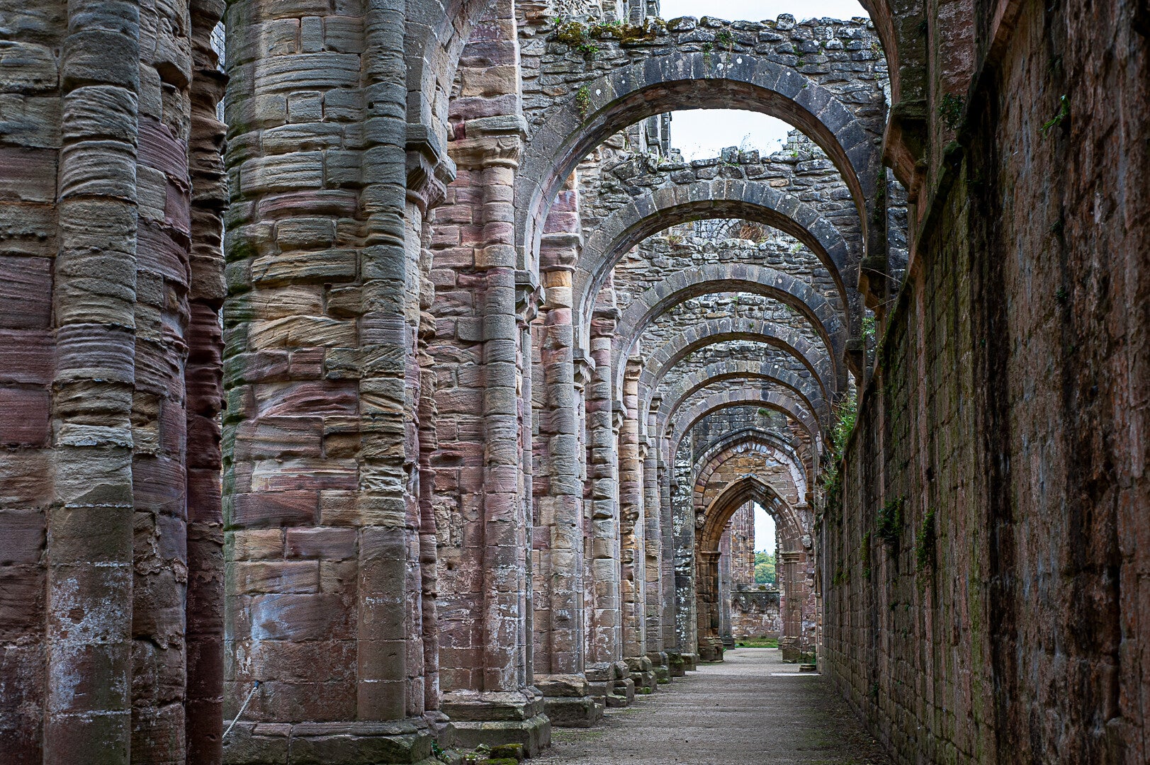 Colour photograph of weathered stone arches and columns in a historic abbey by Robbie Clymo