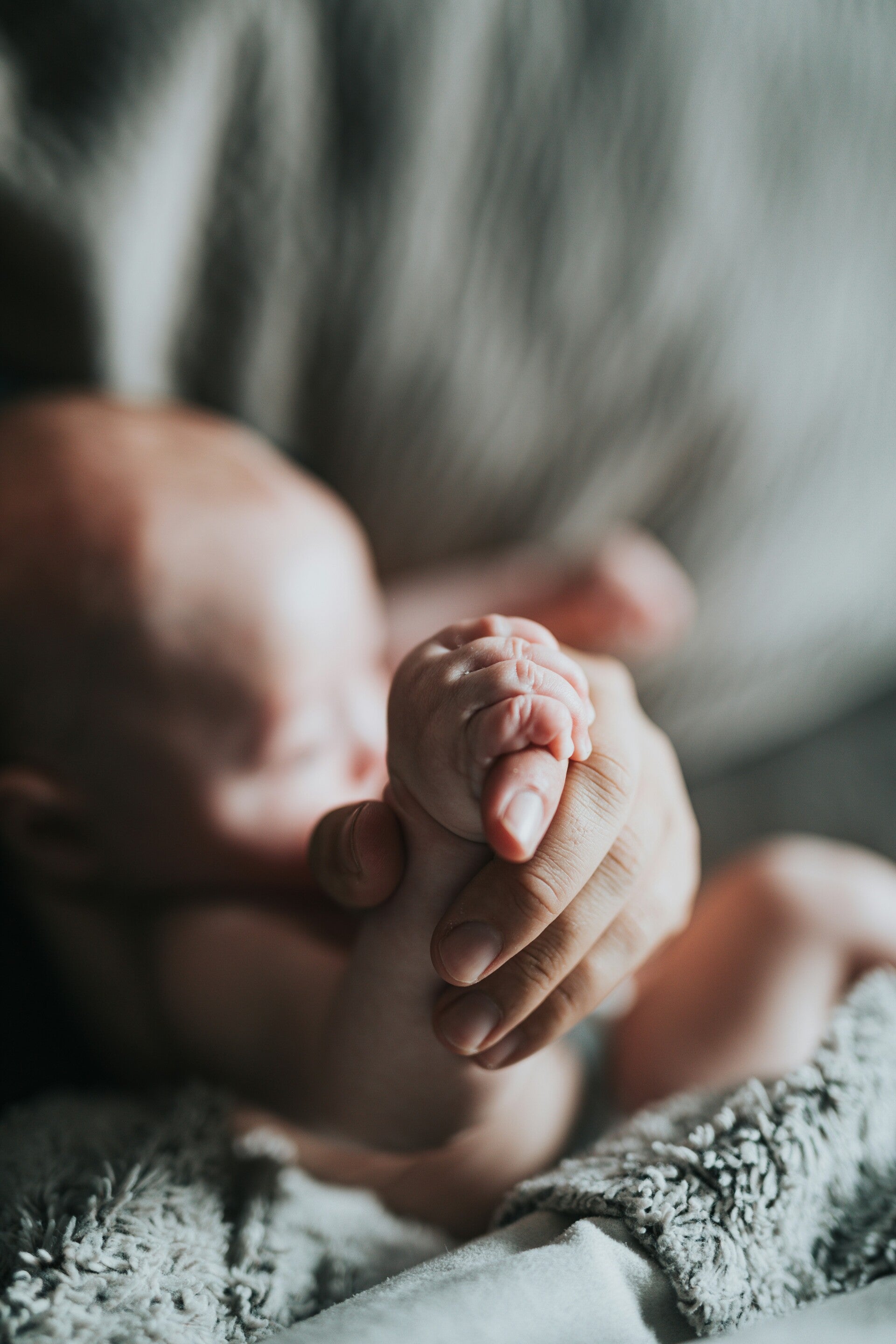 Pasgeboren baby houdt de vinger van de moeder vast in de kraamtijd
