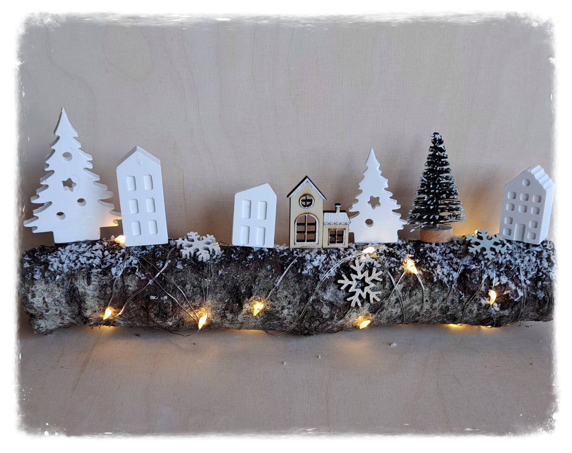Ast mit kleinen Häusern und Lichterkette