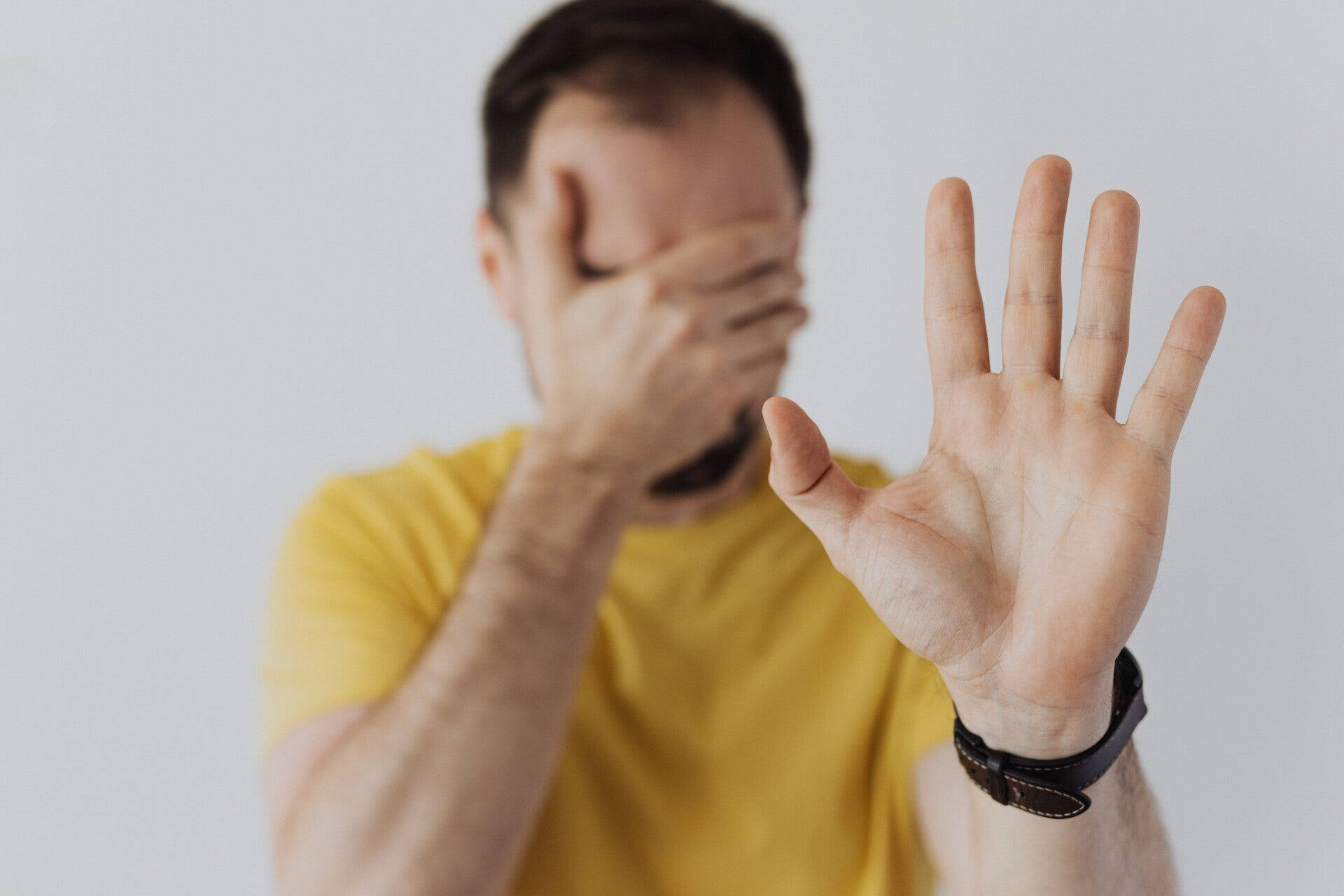 homme qui se cache les yeux et qui marque un stop de la main