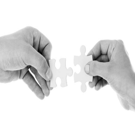 Zwei Hände, die jeweils ein weißes Puzzlestück halten und diese zusammenfügen, symbolisieren Verbindung im Kontext von der kombinierten Sitzung als Jenseitskontakt und Geistführerkontakt mit Medium Jana Lorenz.