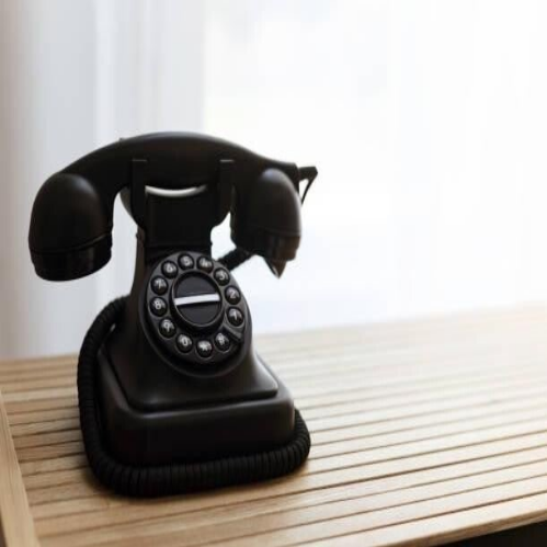 Ein vintage Telefon liegt auf einem Holztablett, das die Eleganz und den Charme vergangener Zeiten widerspiegelt, im Kontext mit Jenseitskontakte Jana Lorenz.