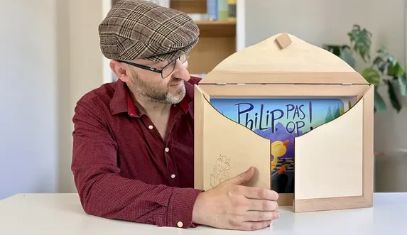 Man opent kamishibai-theater en toont kaart van ‘Philip, pas op!’