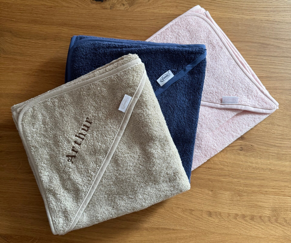 Drie badcapes met naam voor babyโs in zandkleur, blauw en roze โ zachte badstof met geborduurde naam, ideaal als gepersonaliseerd kraamcadeau