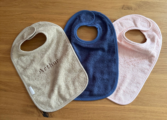 Roze, blauwe en zandkleurige slabbetjes met geborduurde naam – gepersonaliseerde kraamcadeaus van Stitch for kids
