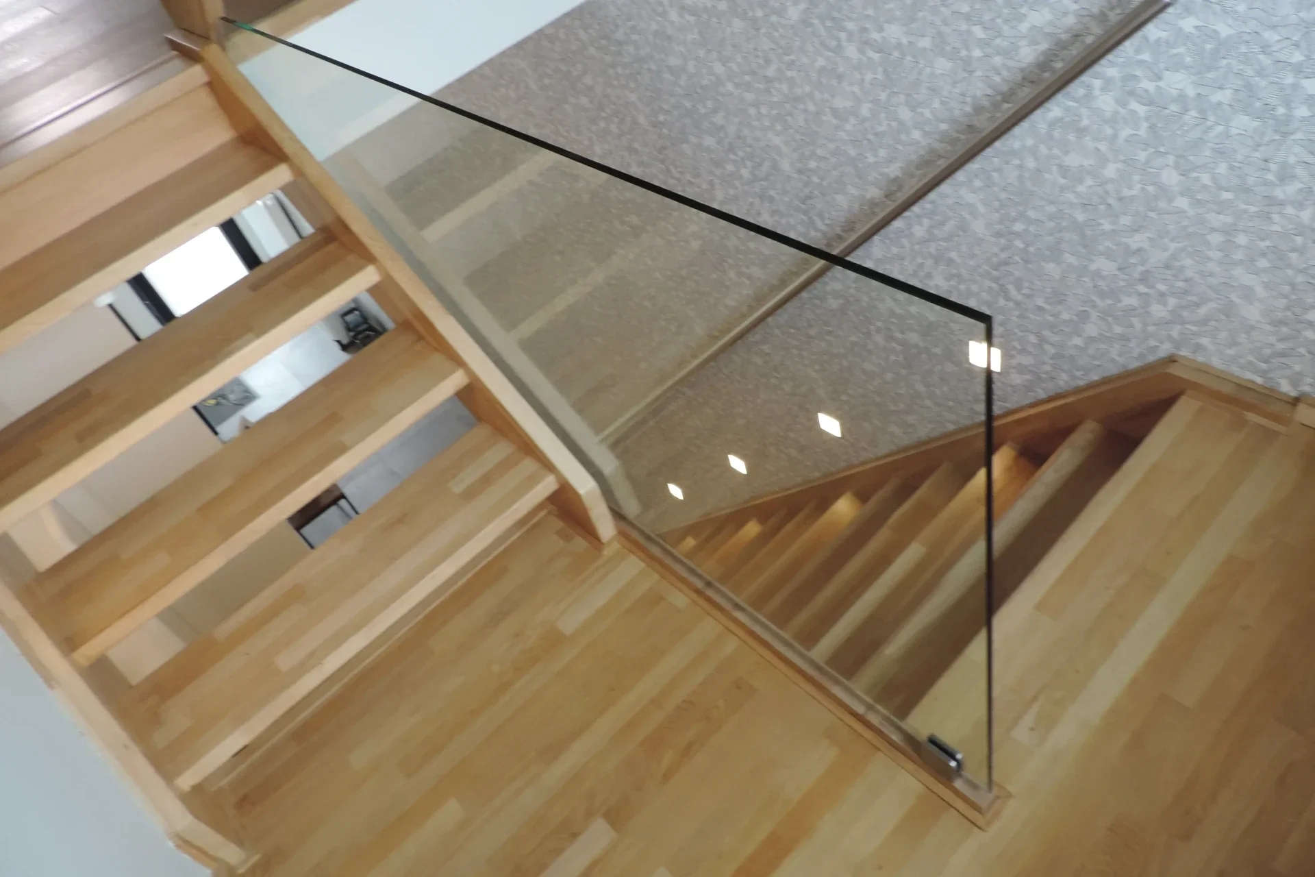 Glasbalustrade gevangen in glasklemmenop houten bordes.