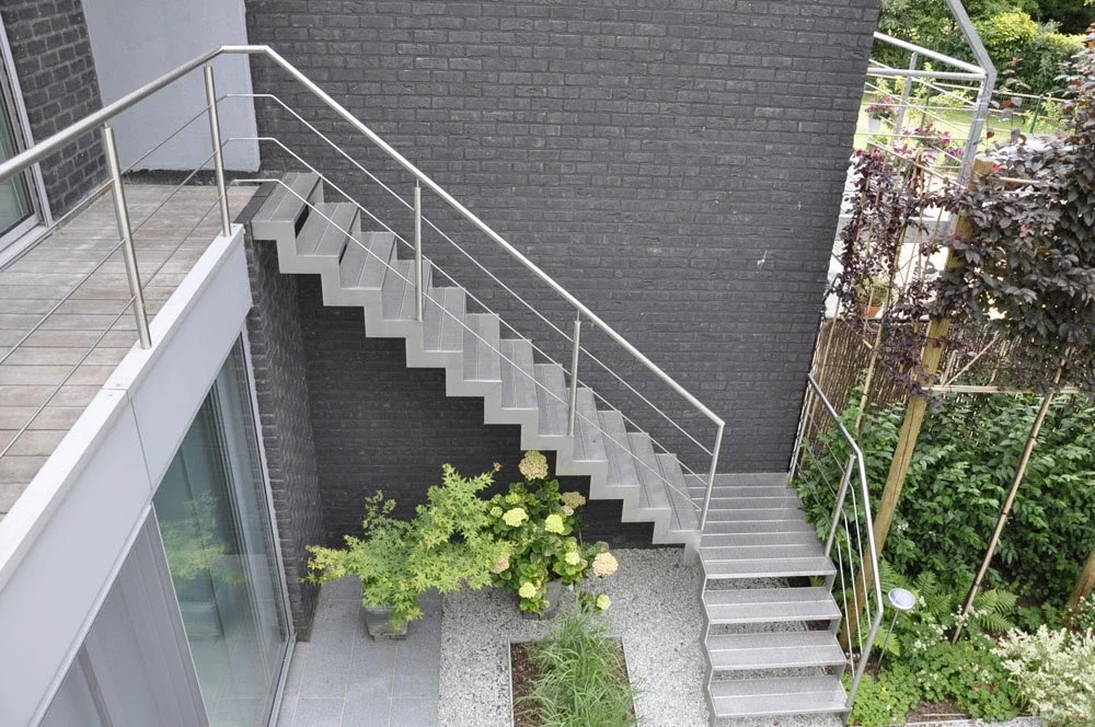 Inox buitentrap met rond geperforeerde treden en balustrade in inox.