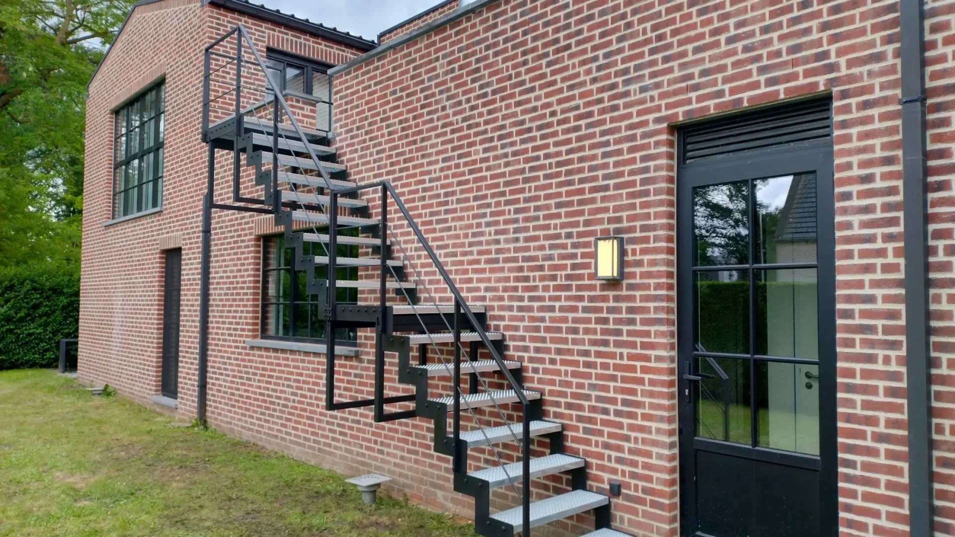 Metalen buitenstrap met trapwangen in z-patroon en gegalvaniseerde geperforeerde treden.