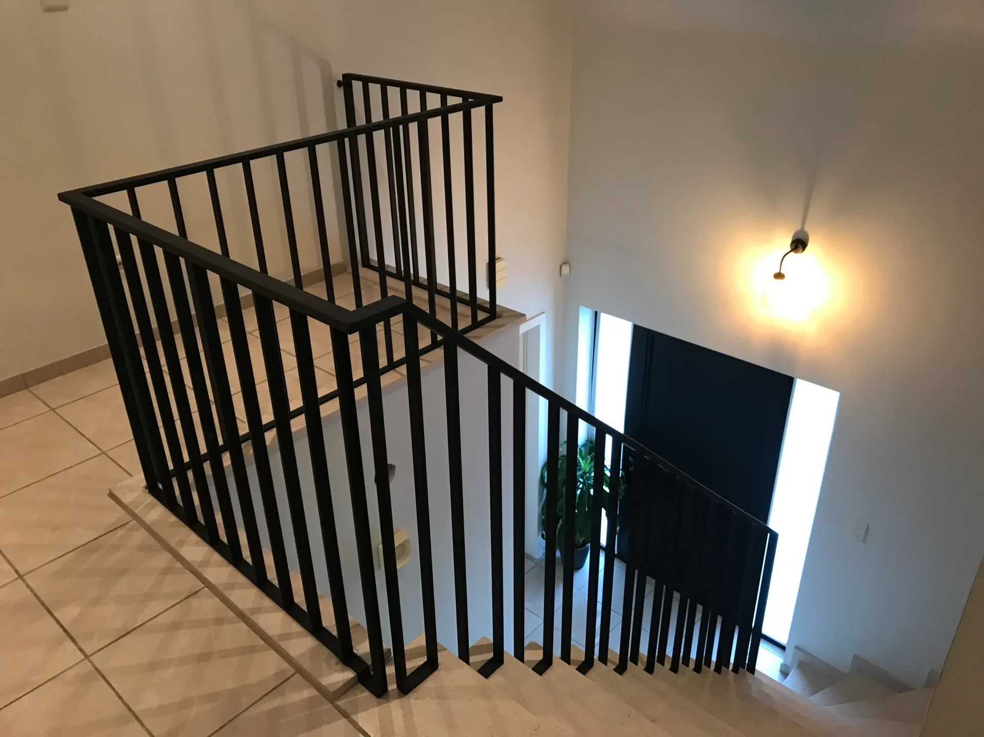 Zwarte metalen balustrade en trapleuning met plaate verticale spijlen.