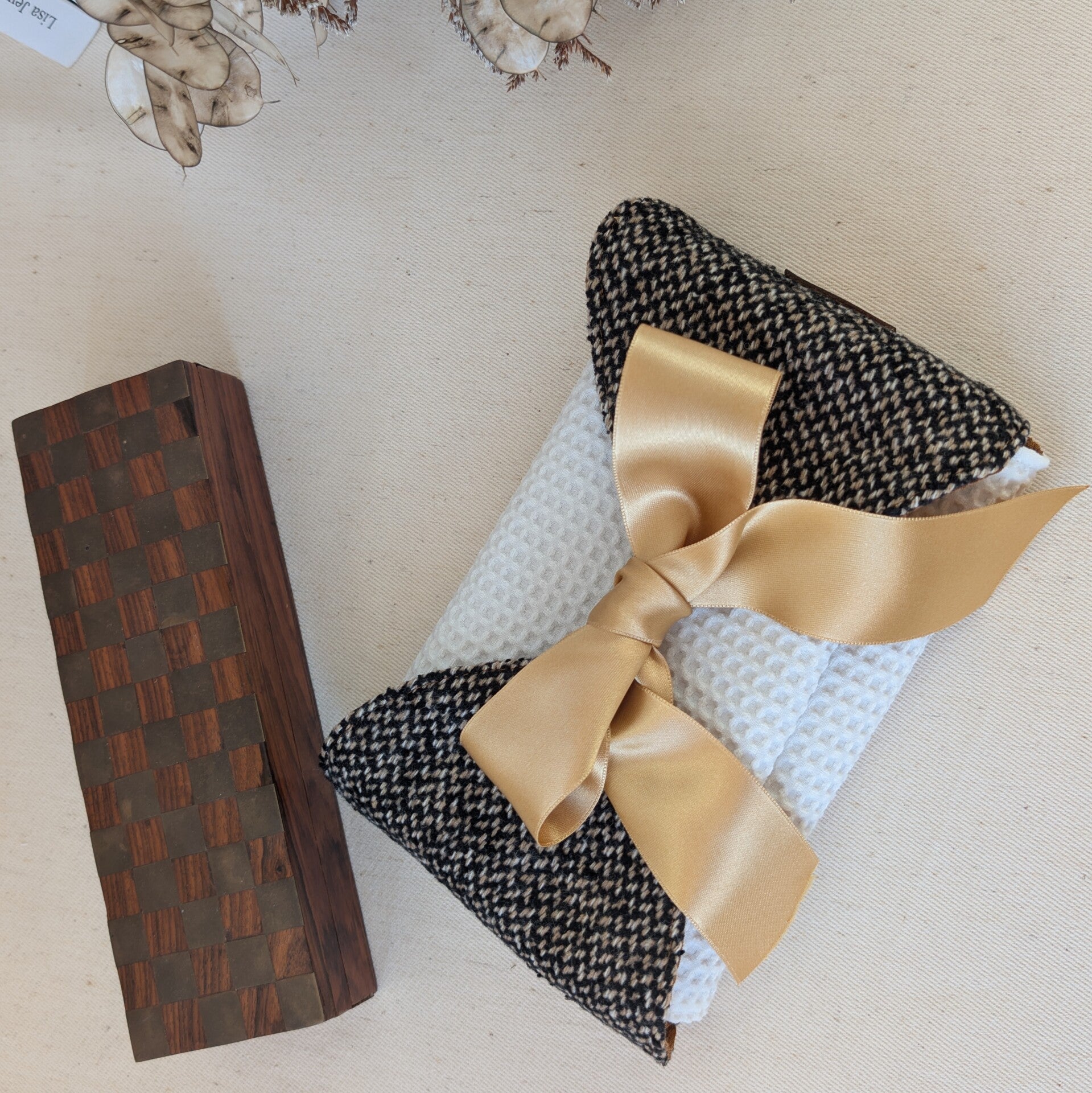 Détail du ruban satiné cousu sur un emballage cadeau pour livre en tissu, finition artisanale