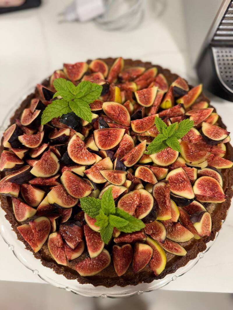 Elegant fresh fig tart with olive oil pastry crust, rich almond frangipane cream, and fresh mint, sophisticated villa catering dessert.